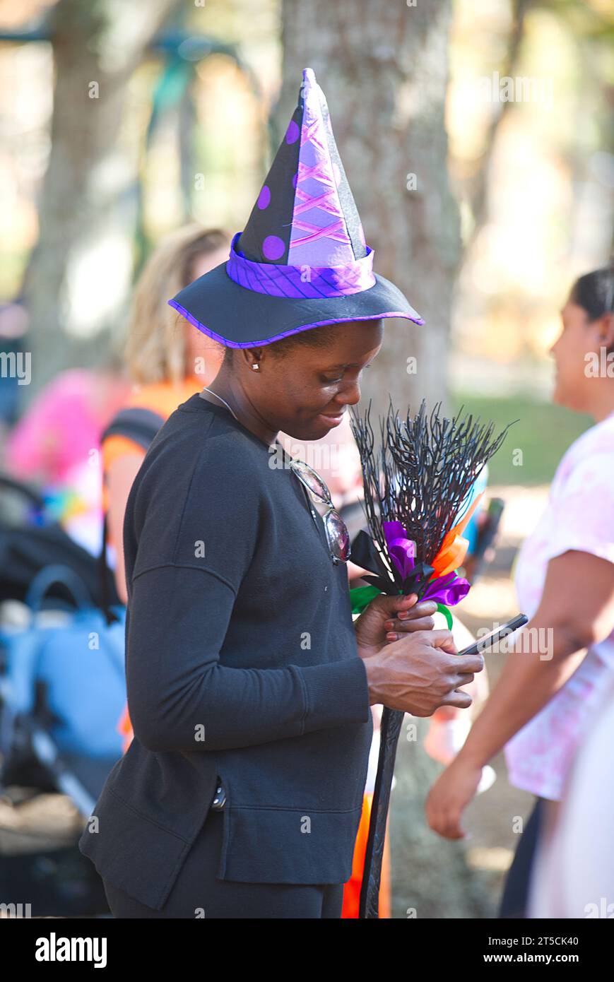 Halloweenpalooza - Dennis, Massachusetts auf Cape Cod. Eine Familienfeier an Halloween. Eine Hexe überprüft ihr Handy. Stockfoto