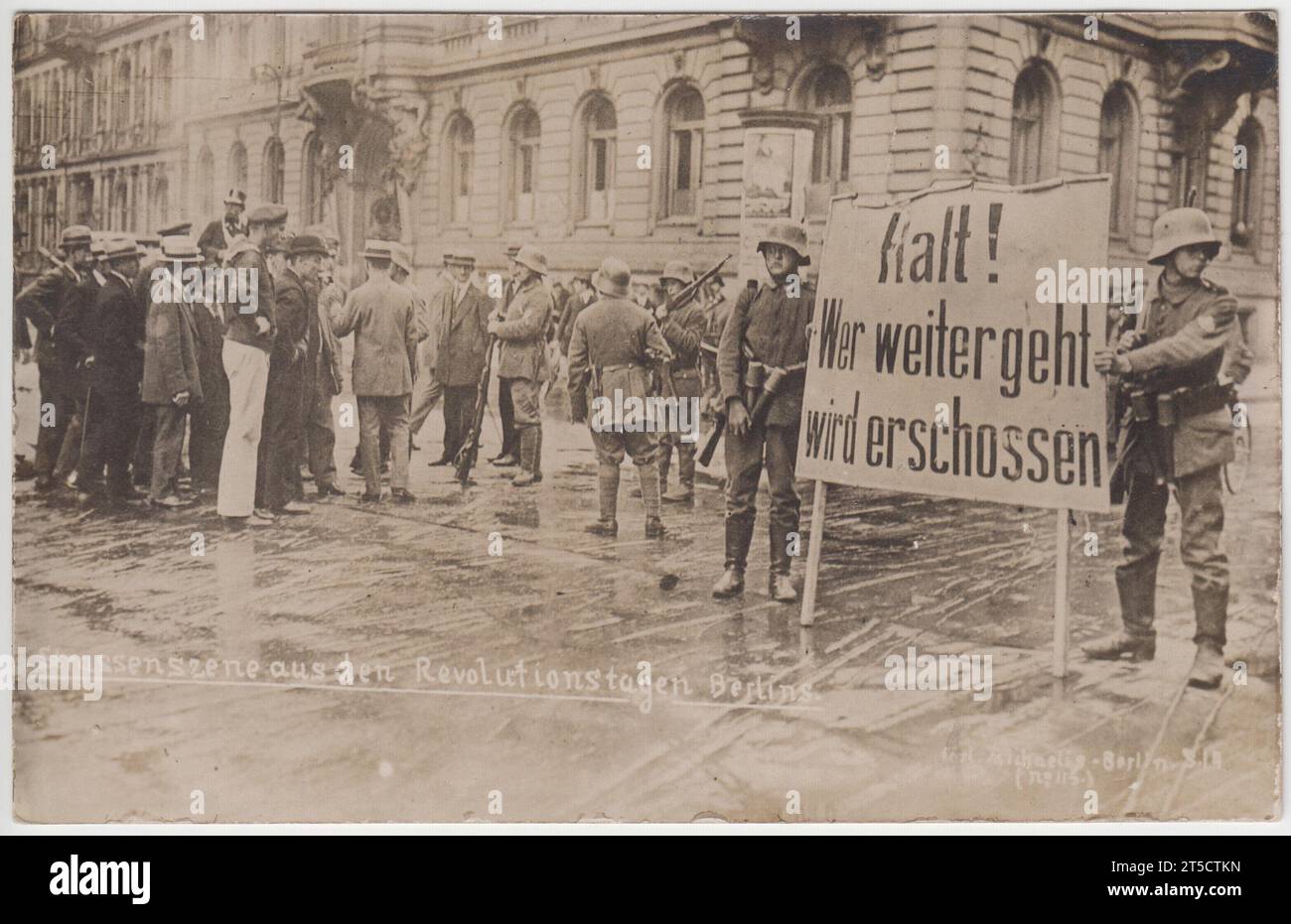 "Strassenszene aus den Revolutionstagen Berlins" / "Straßenszene aus den revolutionären Tagen Berlins": Straßensperre oder militärischer Kontrollpunkt auf den Straßen Berlins während der Deutschen Revolution von 1918 bis 1919, nach dem Ersten Weltkrieg. Zwei uniformierte Soldaten halten eine große Nachricht, auf der steht: "Halt! Wer weitergeht wird erschossen“ / „Stopp! Jeder, der weitermacht, wird erschossen. Andere Soldaten sind im Hintergrund, die eine Gruppe von Männern (einschließlich eines Matrosen) daran hindern, vorbei zu gehen Stockfoto