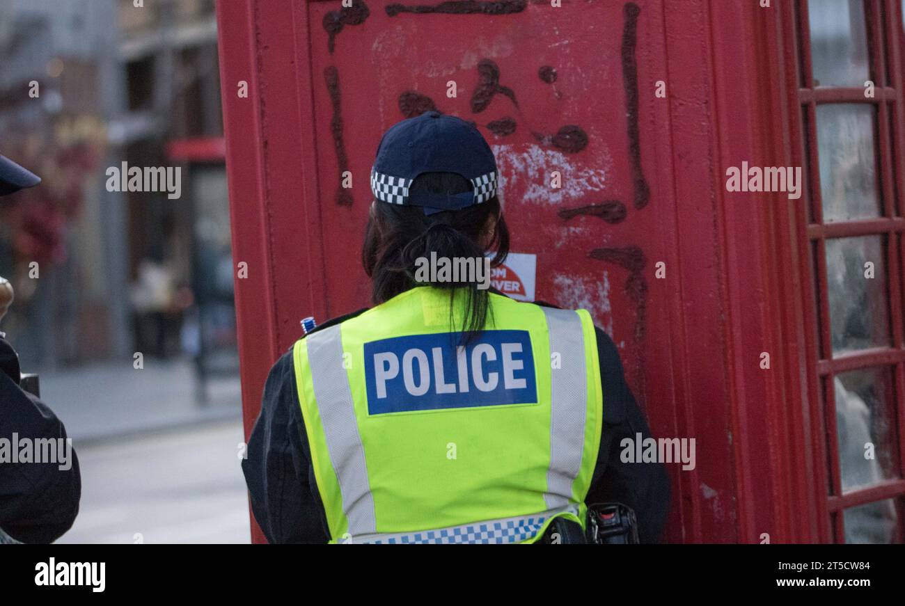 Westminster, London, Großbritannien. November 2023. Der Polizist entfernt ein Poster aus einem Telefonkiosk mit der Aufschrift „vom Fluss zum Meer ist Judenhass“. AS-Gruppen, die die Palästinenser unterstützen, protestieren in Zentral-London als Reaktion auf die anhaltende Krise zwischen Israel und der Hamas im Gazastreifen. Israel erklärte, dass nach dem Angriff der Hamas auf Israel am 7. Oktober ein Kriegszustand zwischen den beiden Regionen besteht, bei dem mehr als 1400 israelische Männer, Frauen und Kinder ums Leben kamen. Die Proteste sind besorgt über die Reaktion des israelischen Militärs. Quelle: Newspics UK London/Alamy Live News Stockfoto