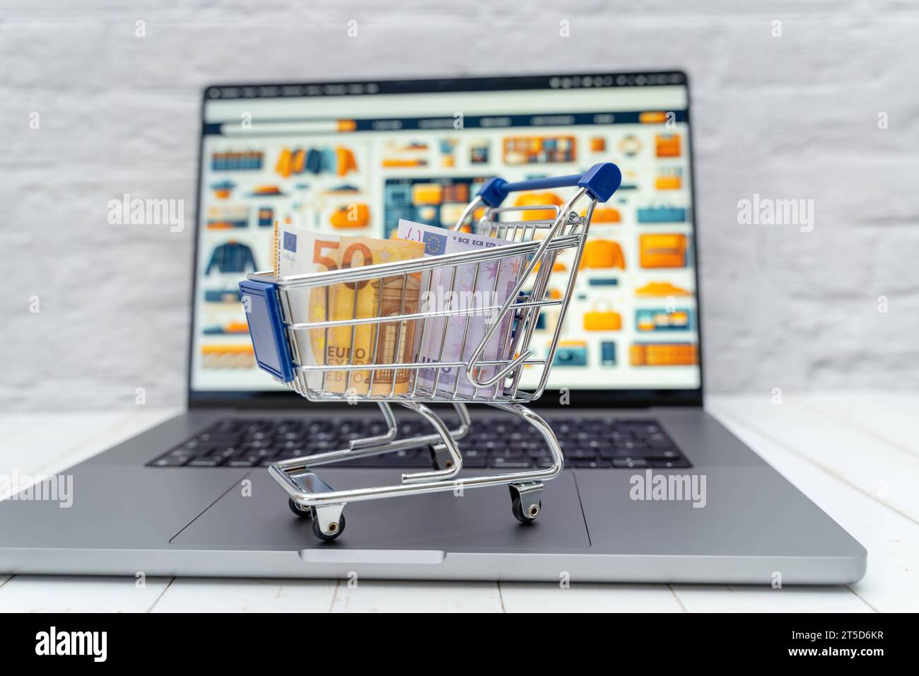 Augsburg, Bayern, Deutschland - 4. November 2023: Einkaufswagen mit Geldscheinen auf einem Laptop Computer vor einem Internet Online-Shop *** Einkaufswagen mit Banknoten auf einem Laptop vor einem Internet-Shop Credit: Imago/Alamy Live News Stockfoto