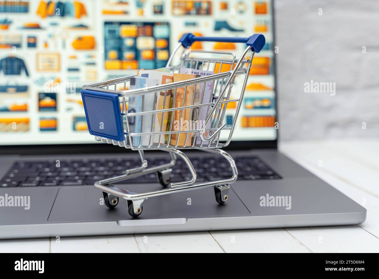 Augsburg, Bayern, Deutschland - 4. November 2023: Einkaufswagen mit Geldscheinen auf einem Laptop Computer vor einem Internet Online-Shop *** Einkaufswagen mit Banknoten auf einem Laptop vor einem Internet-Shop Credit: Imago/Alamy Live News Stockfoto