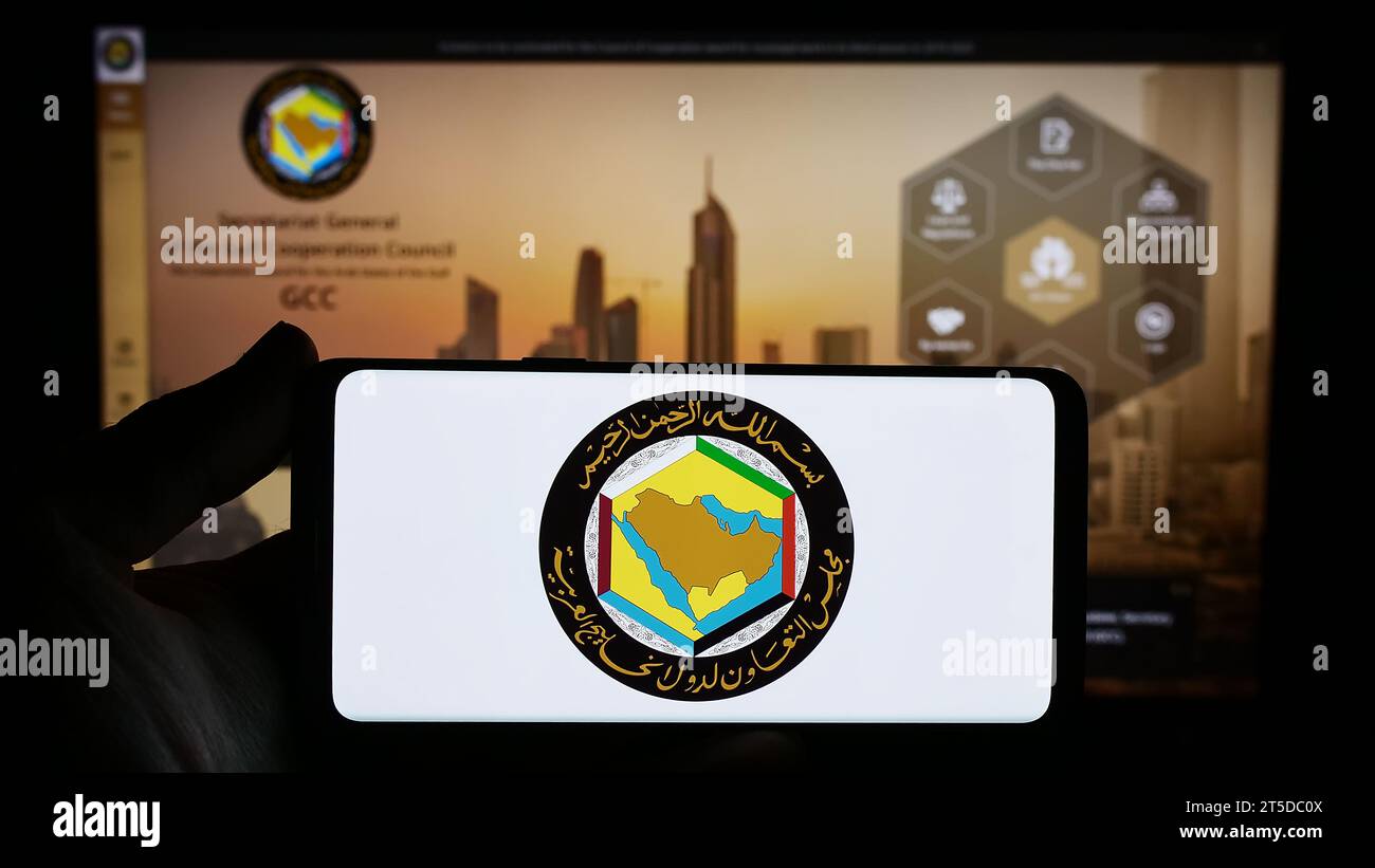 Person mit Smartphone und Logo des Gulf Cooperation Council (GCC) der Arabischen union vor der Website. Schwerpunkt auf dem Display des Telefons. Stockfoto