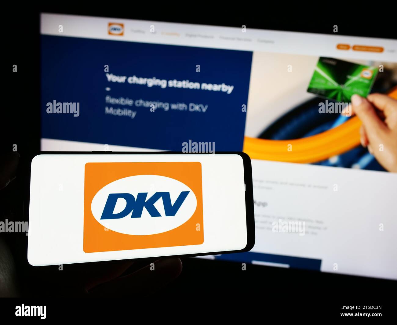 Person mit Handy mit Logo des deutschen B2B-Zahlungsunternehmens DKV Mobility vor der Business-Website. Schwerpunkt auf dem Display des Telefons. Stockfoto