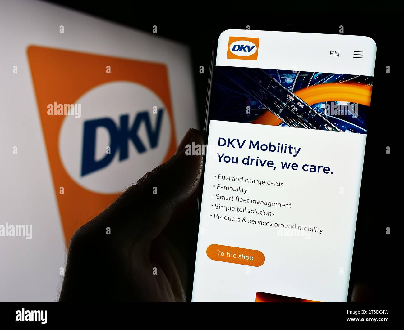 Handybesitzer mit Webseite des deutschen B2B-Zahlungsunternehmens DKV Mobility vor dem Firmenlogo. Konzentrieren Sie sich auf die Mitte des Telefondisplays. Stockfoto