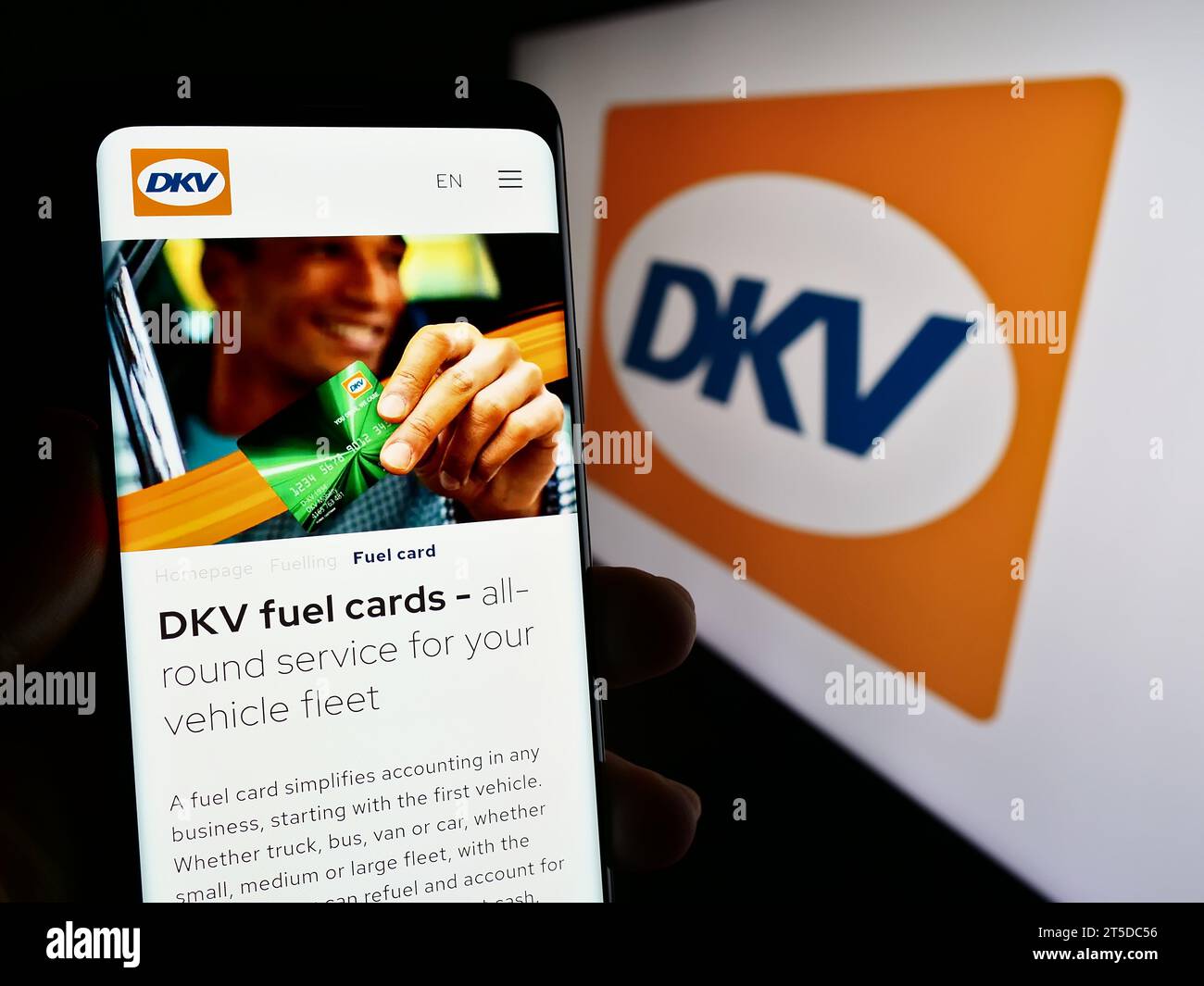 Person mit Mobiltelefon mit Webseite des deutschen B2B-Zahlungsunternehmens DKV Mobility vor Logo. Konzentrieren Sie sich auf die Mitte des Telefondisplays. Stockfoto