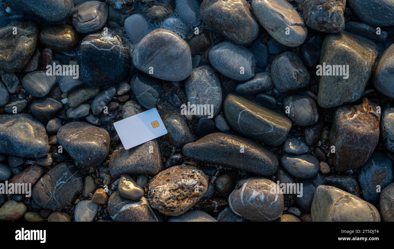 Weiße Bankkarte auf glatten grauen Steinen, die die Kreuzung von Geld und Natur symbolisiert. Kopierbereich. Stockfoto