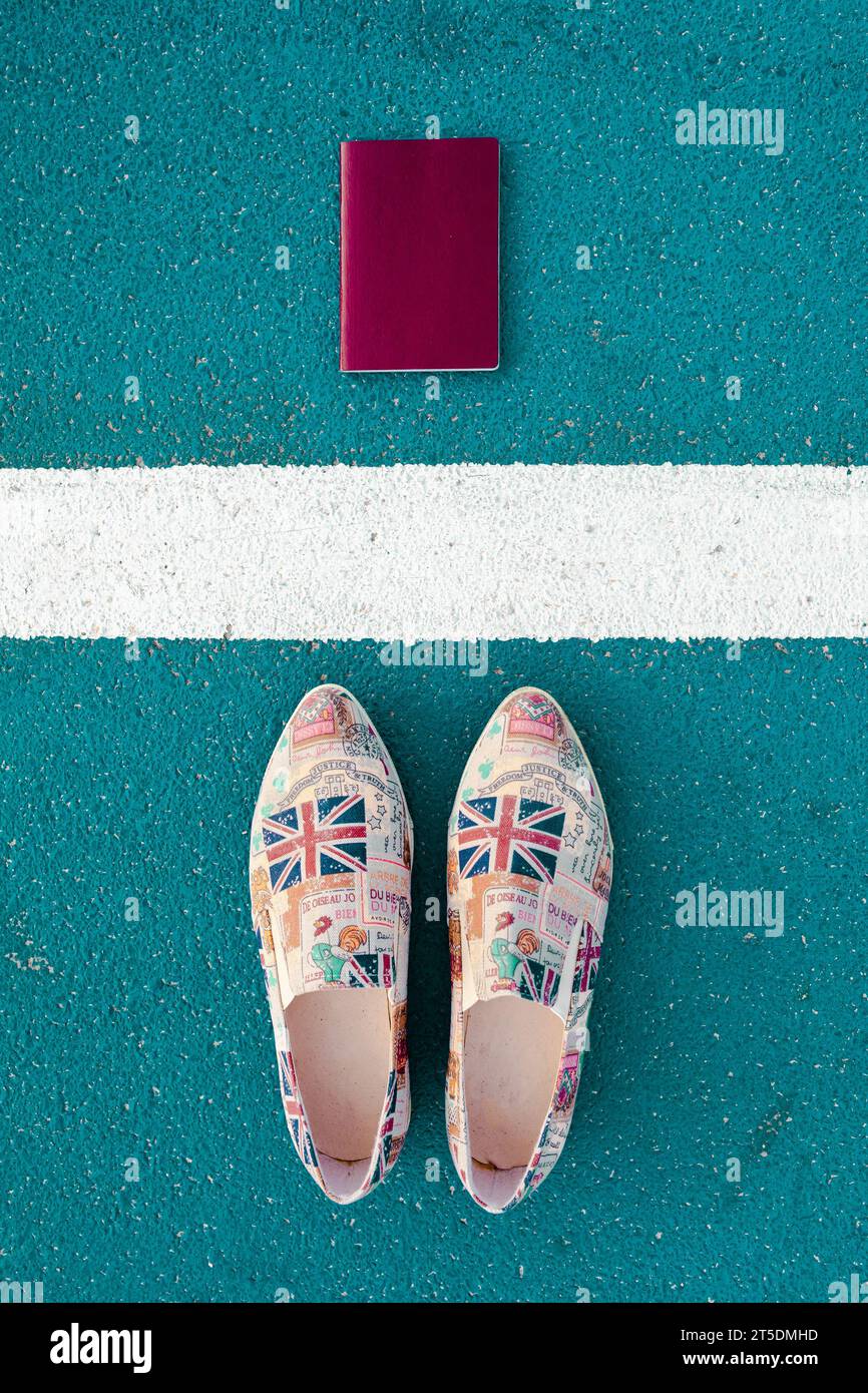 Blick von oben auf ein Paar Schuhe, die mit Symbolen von Großbritannien und Frankreich bedeckt sind, neben einem Pass Stockfoto
