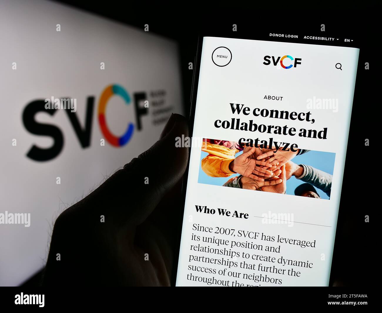 Person, die ein Mobiltelefon hält, mit Webseite der US-Organisation Silicon Valley Community Foundation (SVCF) mit Logo. Konzentrieren Sie sich auf die Mitte des Telefondisplays. Stockfoto