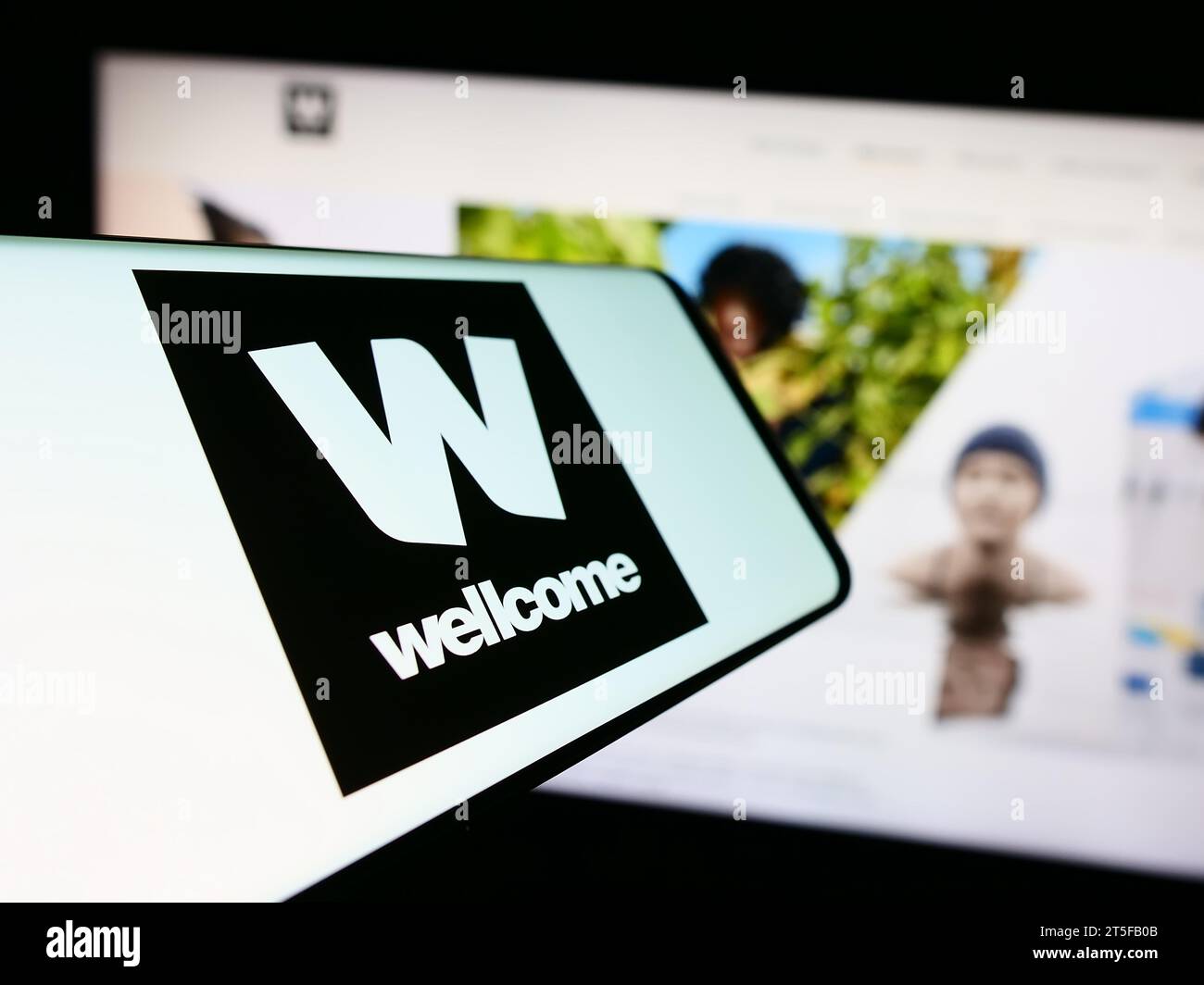 Mobiltelefon mit Logo der britischen Wohltätigkeitsstiftung Wellcome Trust vor der Website. Konzentrieren Sie sich auf die Mitte des Telefondisplays. Stockfoto