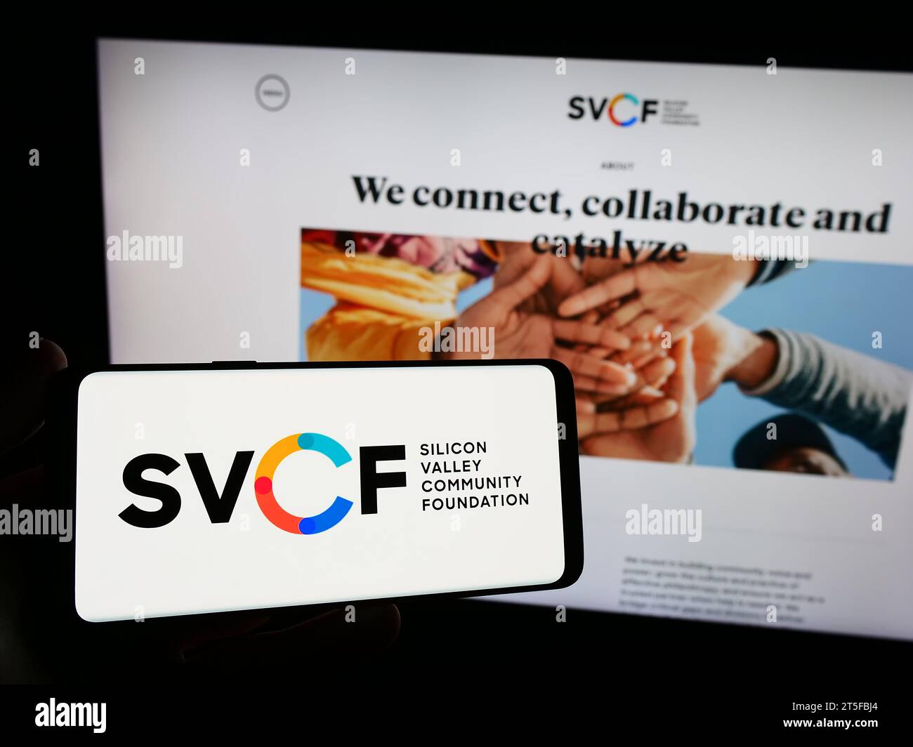Person mit Smartphone und Logo der US-Organisation Silicon Valley Community Foundation (SVCF) vor der Website. Schwerpunkt auf dem Display des Telefons. Stockfoto