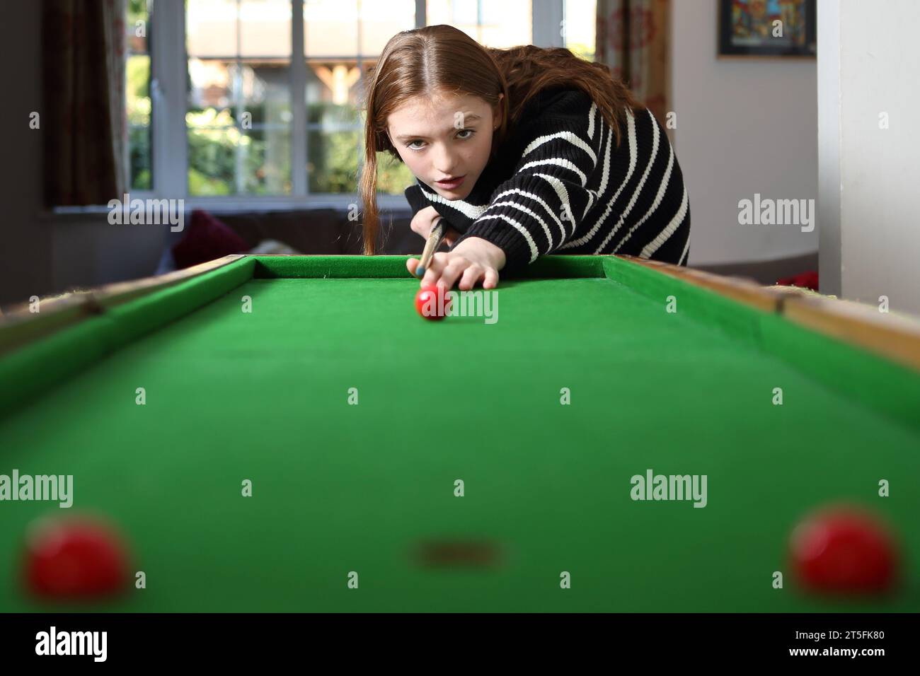 Teenager-Mädchen, das traditionelle Pub-Spiel Bagatelle in der Lounge zu Hause spielt Stockfoto