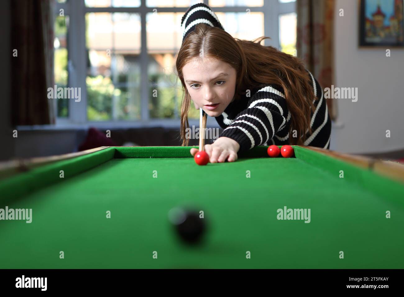 Teenager-Mädchen, das traditionelle Pub-Spiel Bagatelle in der Lounge zu Hause spielt Stockfoto