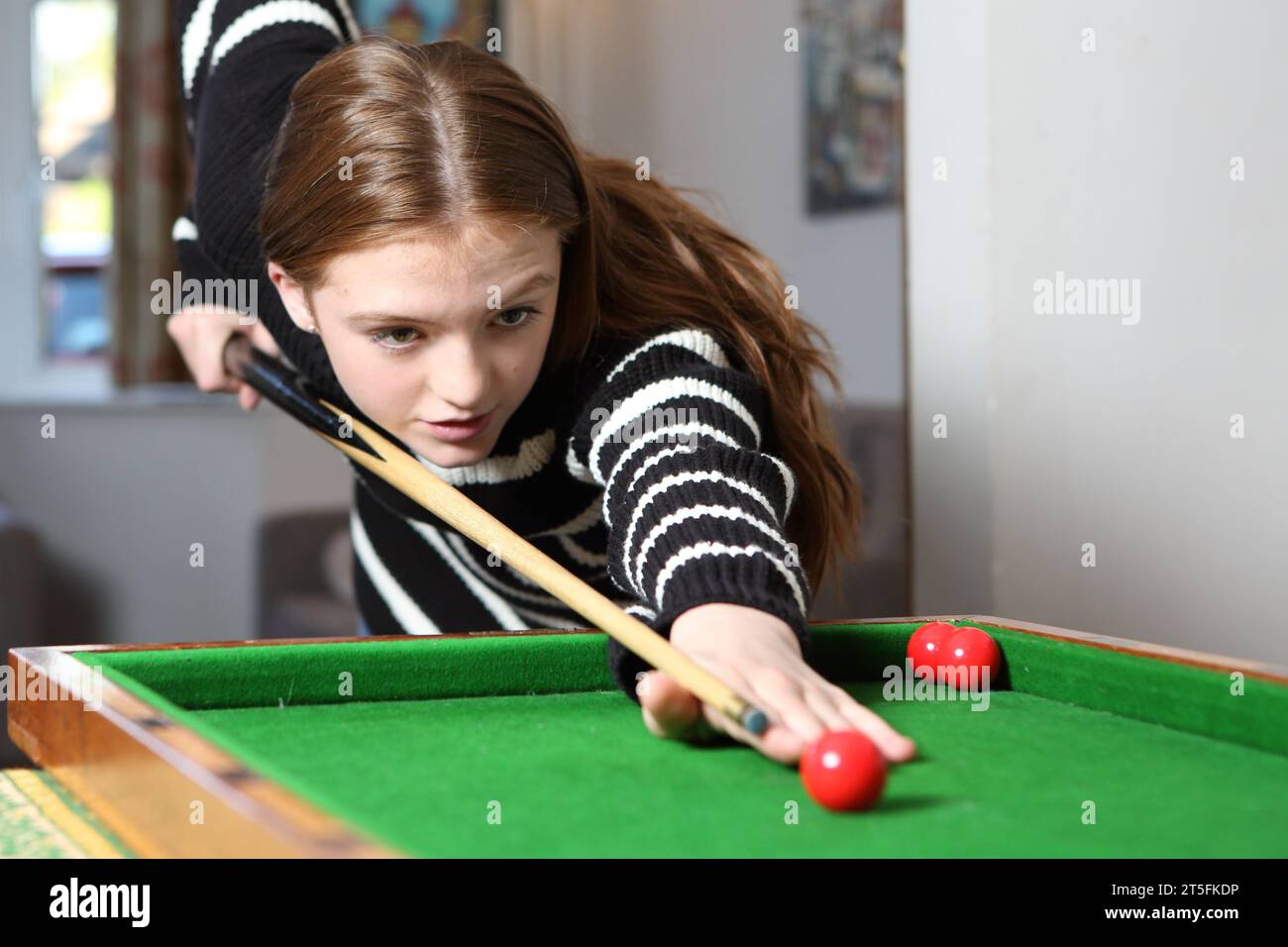 Teenager-Mädchen, das traditionelle Pub-Spiel Bagatelle in der Lounge zu Hause spielt Stockfoto