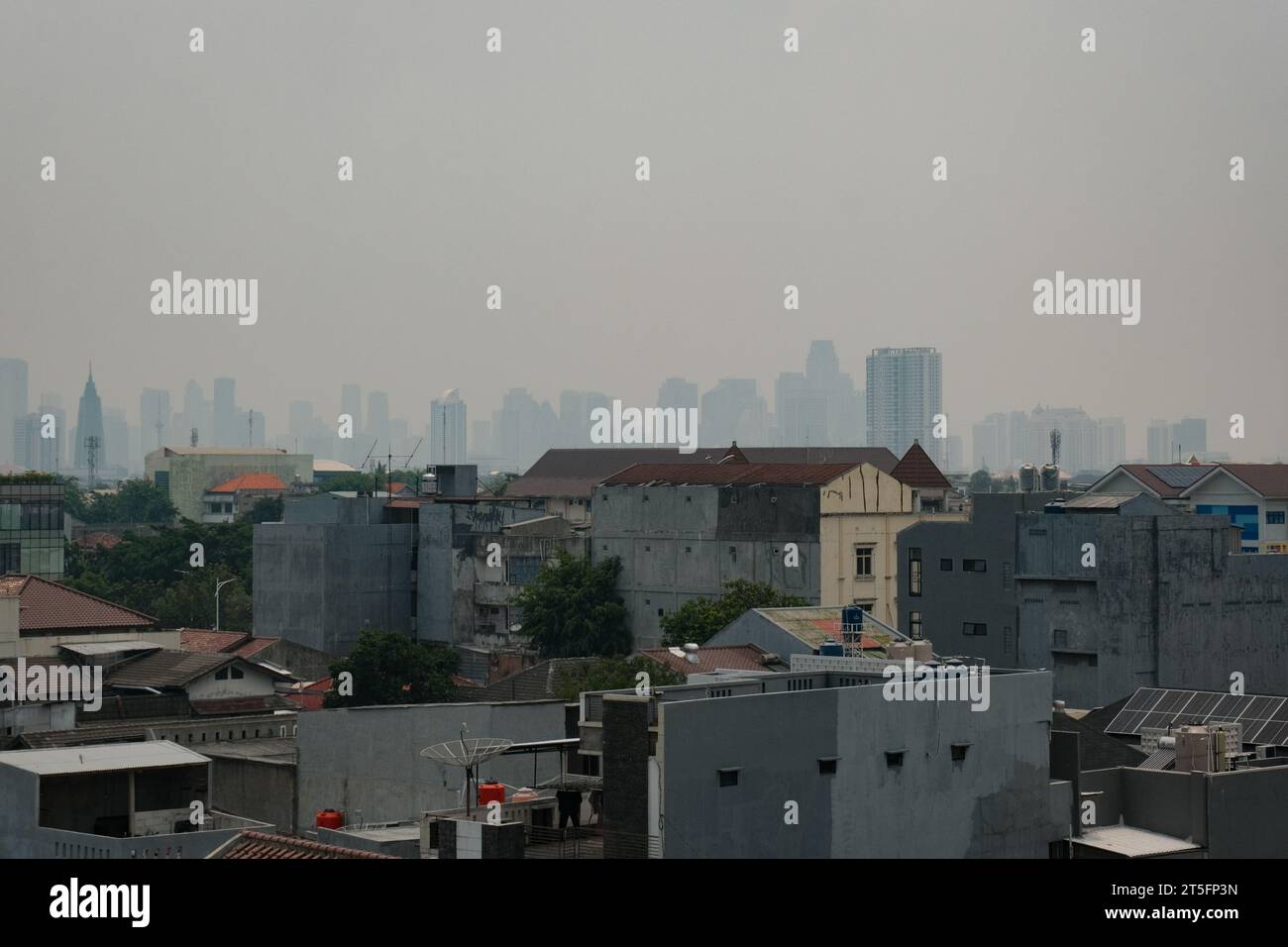 Erleben Sie die städtischen Wandteppiche von Jakarta: Gebäude der Mittelklasse, standhaft und stolz, gegenübergestellt von nebeligen Wolkenkratzern, Symbole des Wohlstands in der Stockfoto