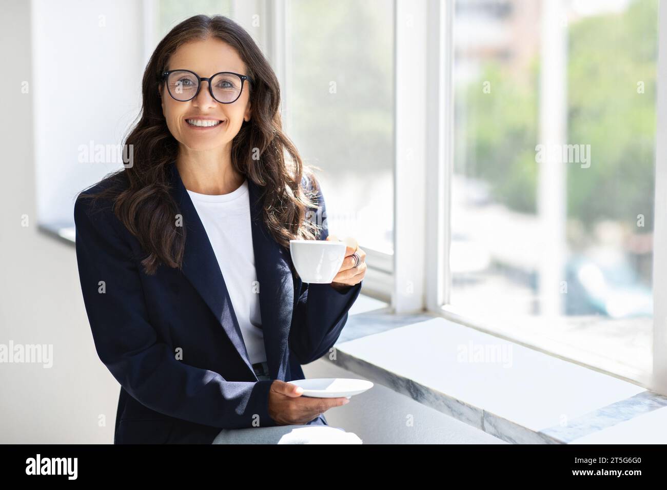Reife Geschäftsfrau mit Brille und Kaffee im Büro Stockfoto