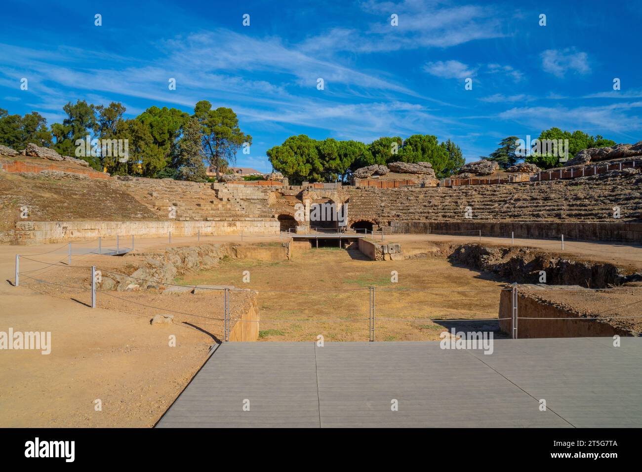 Blick vom hölzernen Fußweg auf die Arena des römischen Amphitheaters von Mérida, beleuchtet durch das Licht der Morgendämmerung, die Schatten auf seinen Ständen mit dem erzeugt Stockfoto