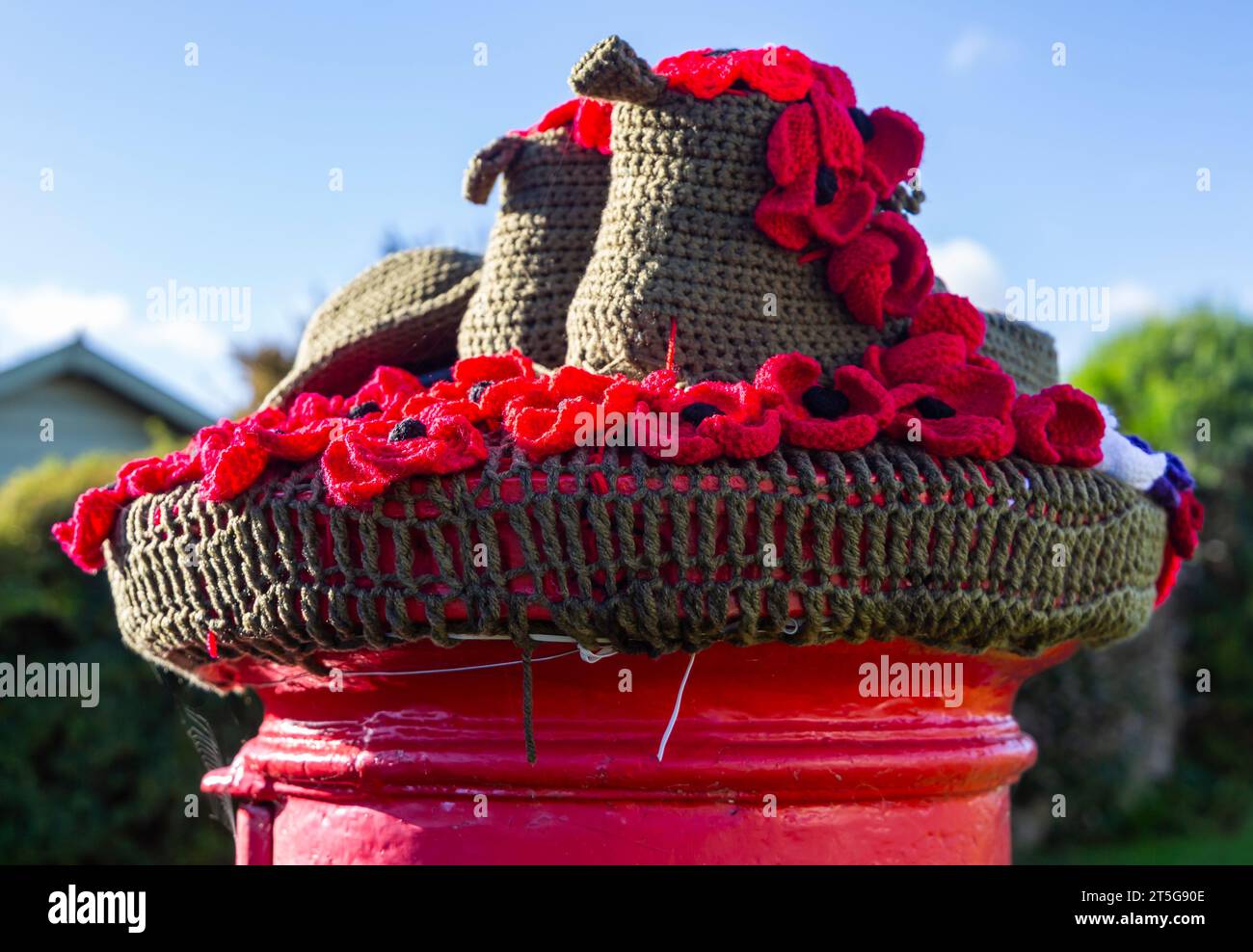 Poole, Dorset, Großbritannien. November 2023. Ein ergreifender gestrickter Briefkasten-Topper aus Soldatenstiefeln und -Hut und roten Mohnblumen in Poole, Dorset, als der Gedenktag naht und wir erinnern uns an die, die tapfer in den Kriegen gekämpft haben. - Briefkastendeckel, Briefkastendeckel, Briefkastendeckel, Topper, Garnbombardierung, Garnbombe. Quelle: Carolyn Jenkins/Alamy Live News Stockfoto