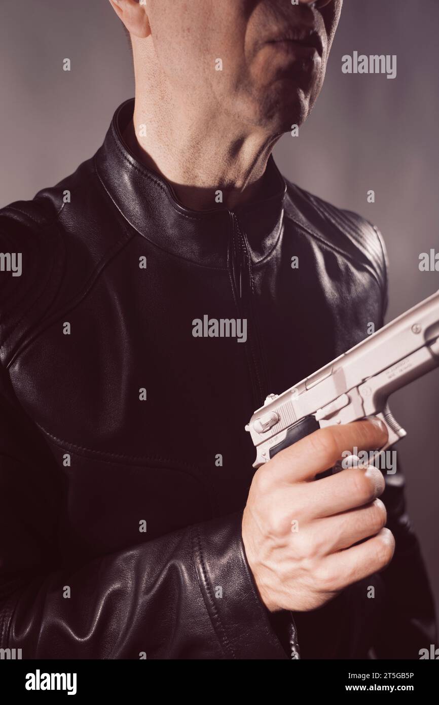Schwarze Lederjacke Mörder Detective Spion Mörder Attentäter mit Gewehrporträt Foto. Stockfoto