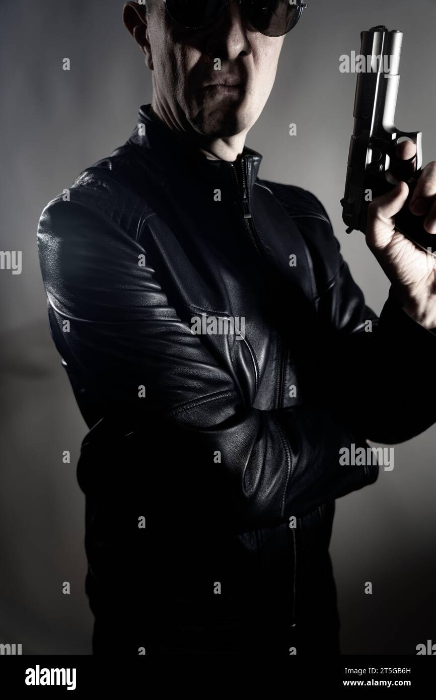 Schwarze Lederjacke Mörder Detective Spion Mörder Attentäter mit Gewehrporträt Foto. Stockfoto