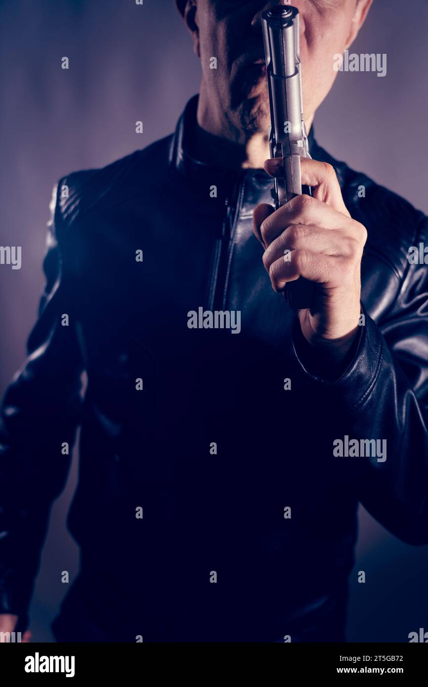 Schwarze Lederjacke Mörder Detective Spion Mörder Attentäter mit Gewehrporträt Foto. Stockfoto