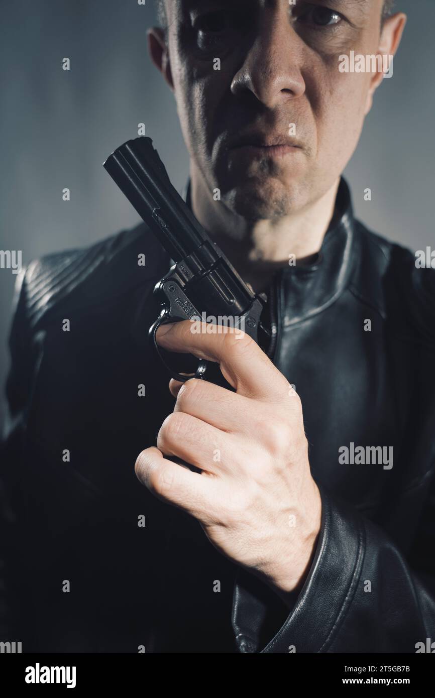 Schwarze Lederjacke Mörder Detective Spion Mörder Attentäter mit Gewehrporträt Foto. Stockfoto