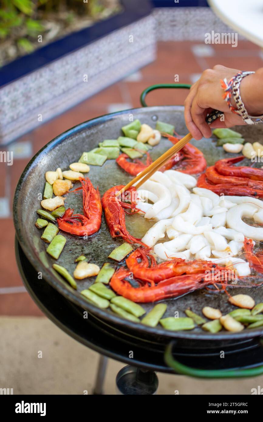 Bild des Kochprozesses von Paella in vertrauter Umgebung. Spanisches Rezept Stockfoto