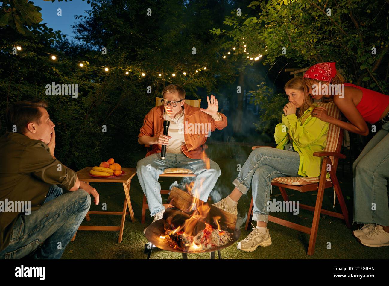 Teenager, der Spaß am Lagerfeuer hat und Horrorgeschichten erzählt, die Zeit auf dem Campingplatz verbringen Stockfoto