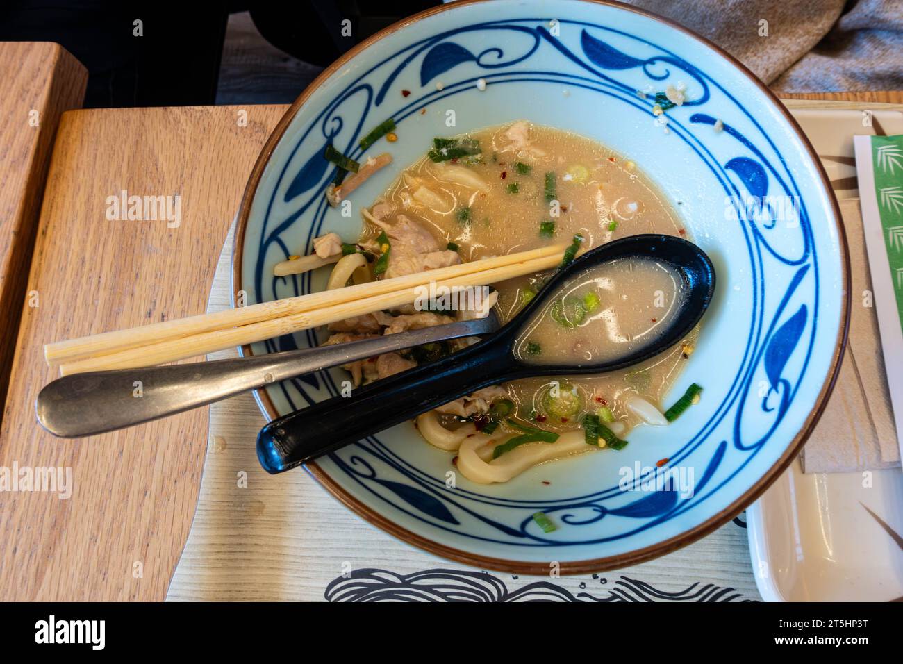 Eine Schüssel mit Resten von Suppe und Nudeln, nachdem eine Person eine Mahlzeit in einem Restaurant beendet hat Stockfoto