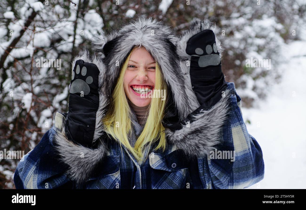 Glückliche junge Frau im schneebedeckten Winterpark, die draußen warme Kleidung trägt. Mädchen genießt den Winter. Warme Kleidung für kaltes Wetter. Schneebedeckter Wintertag. Schön Stockfoto