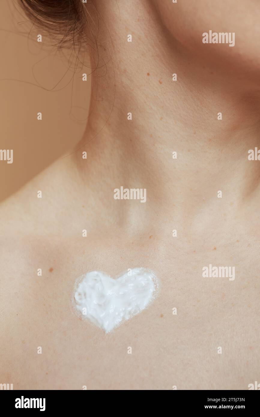 Großaufnahme einer modernen 40-jährigen Frau mit herzförmiger Creme auf der Brust. Stockfoto