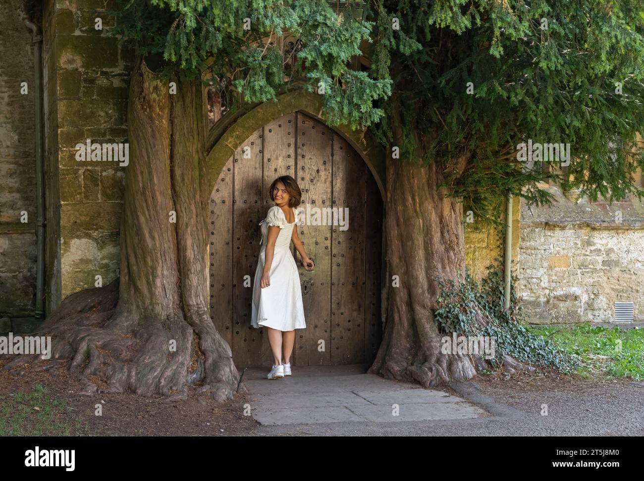 Stau on the Wold, Cotswolds, Worcestershire, Großbritannien - 14. September 2022 - schöne Frau in einem weißen Kleid und stehend an einer Tür nach hinten Stockfoto