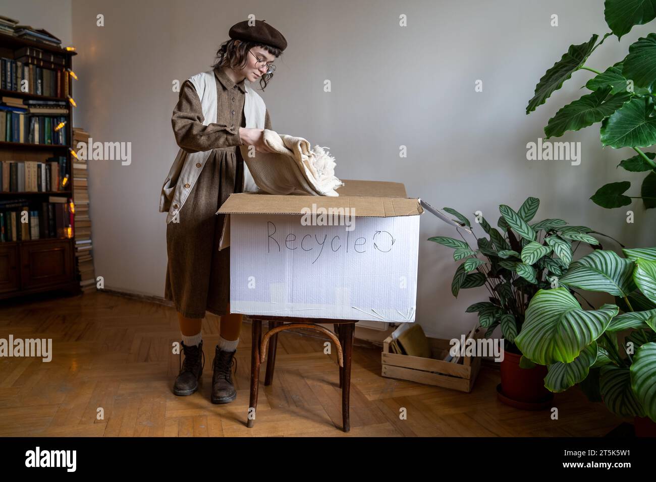 Umweltfreundliches Teenager-Mädchen, das alte Kleidung aus Bio-Baumwolle in Pappkarton für Recycling und Wiederverwendung verpackt Stockfoto