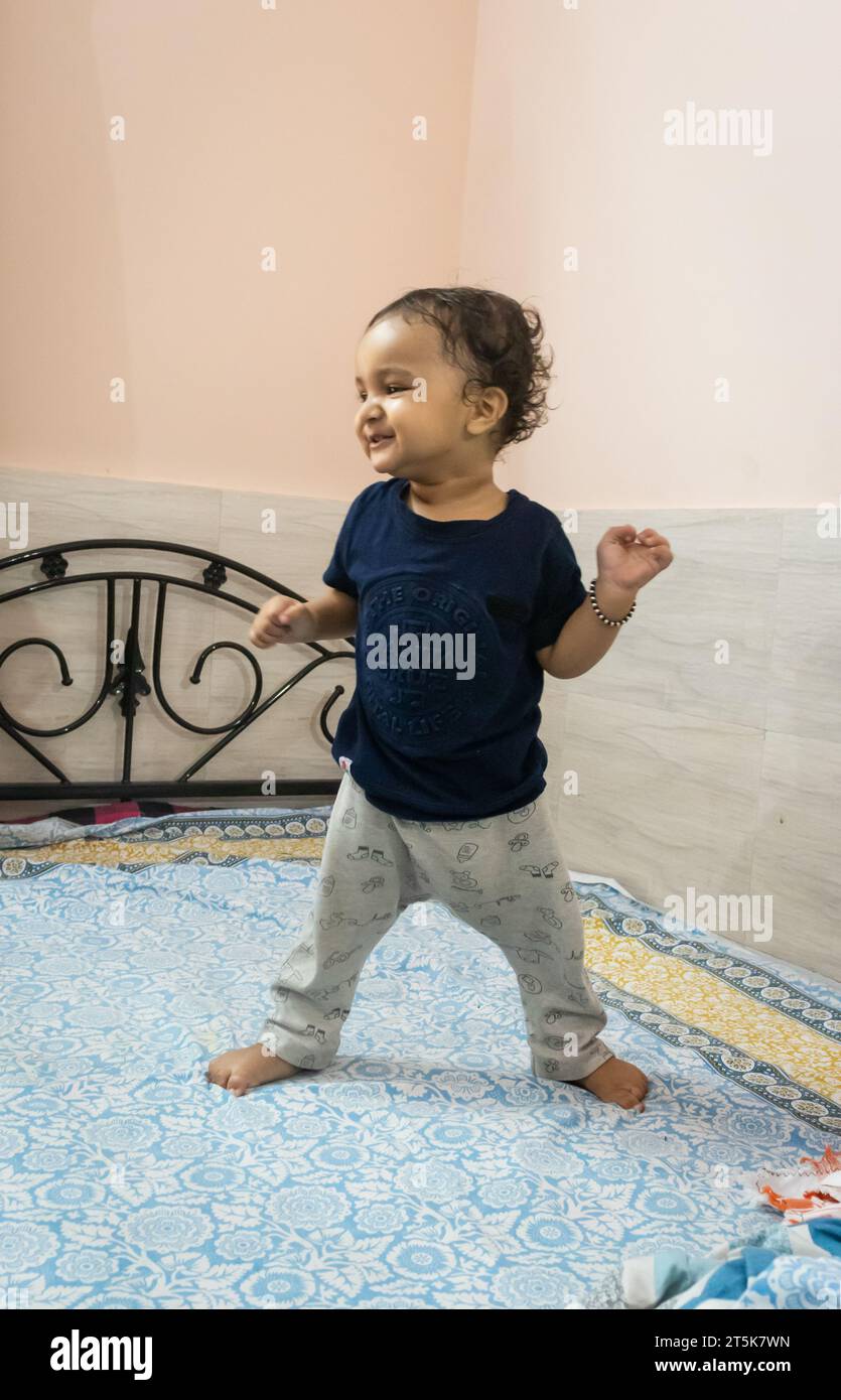 Niedlicher Kleinkind, der versucht, zum ersten Mal im Bett zu Hause zu stehen Stockfoto