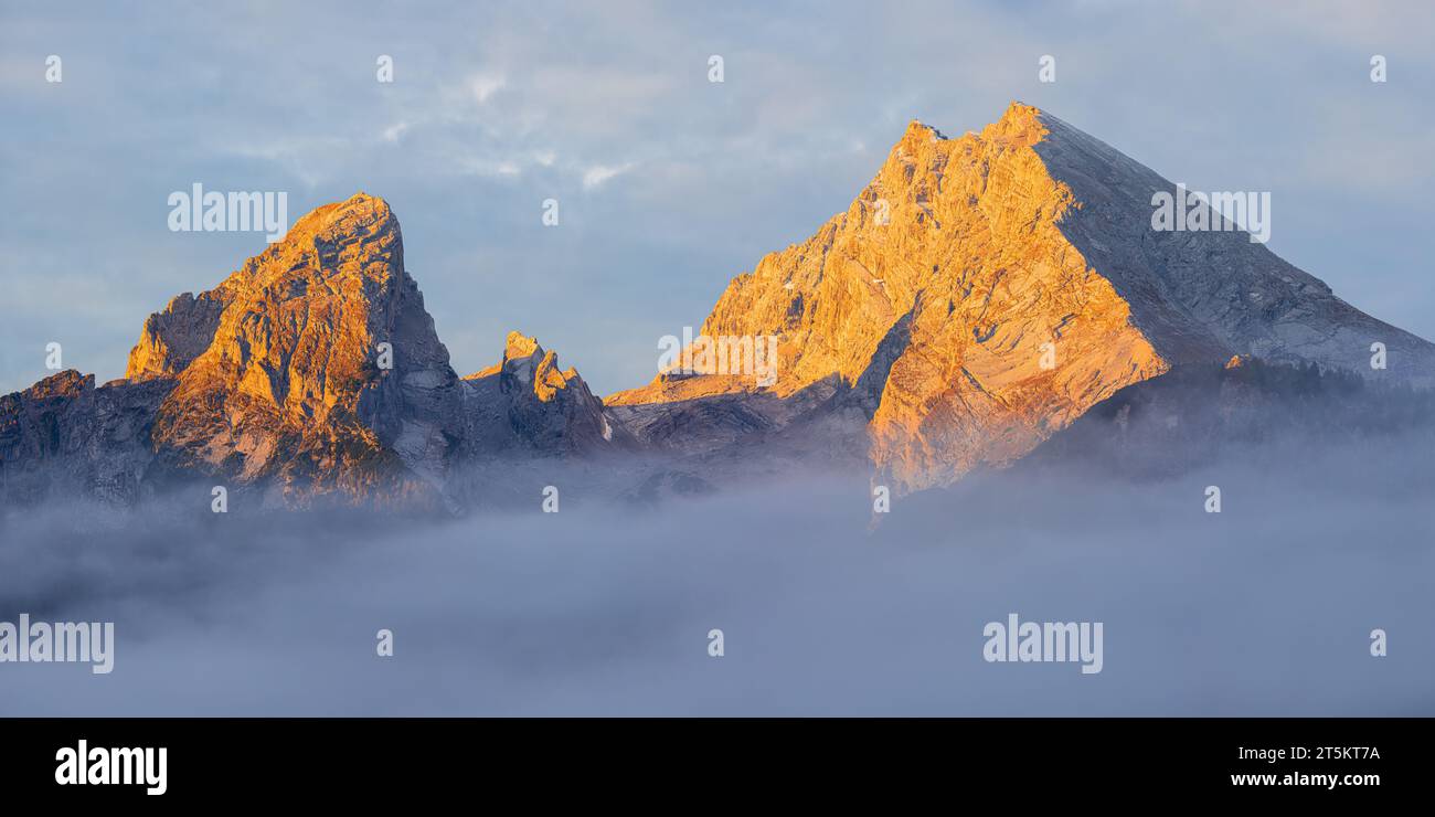 Ein breites 2:1-Panoramabild von einem Sonnenaufgang im Herbst am Watzmann, der sich über den Wolken bei Berchtesgaden im Berchtesgadener Land erhebt Stockfoto