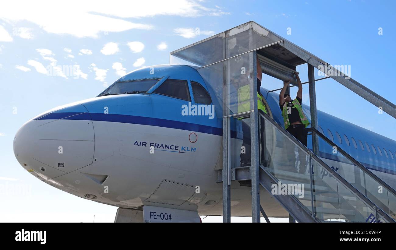 Schiphol, Niederlande - 14. August 2023 zwei Mitarbeiter des Internationalen Flughafens Schiphol installieren am Eingang zum Fokker von KLM einen Rollladen Stockfoto