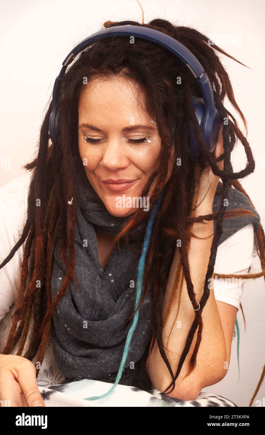 Alternative Bohemian Frau mit Dreadlocks und Kopfhörern Inhalt und Lächeln Stockfoto