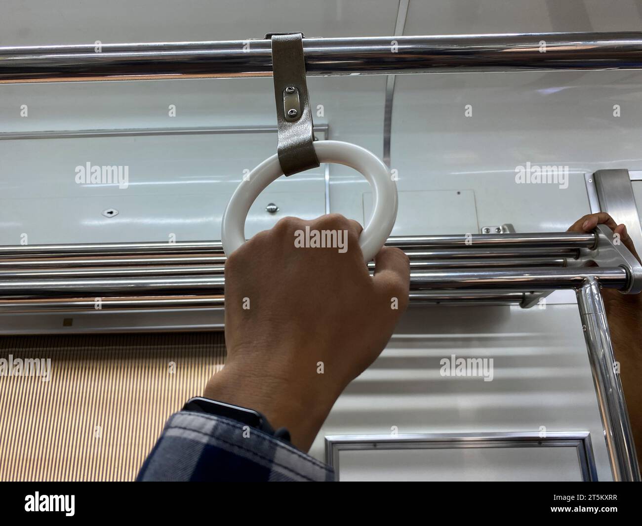 Die Hand des Mannes am Handgriff in der Pendlerlinie in Jakarta Stockfoto