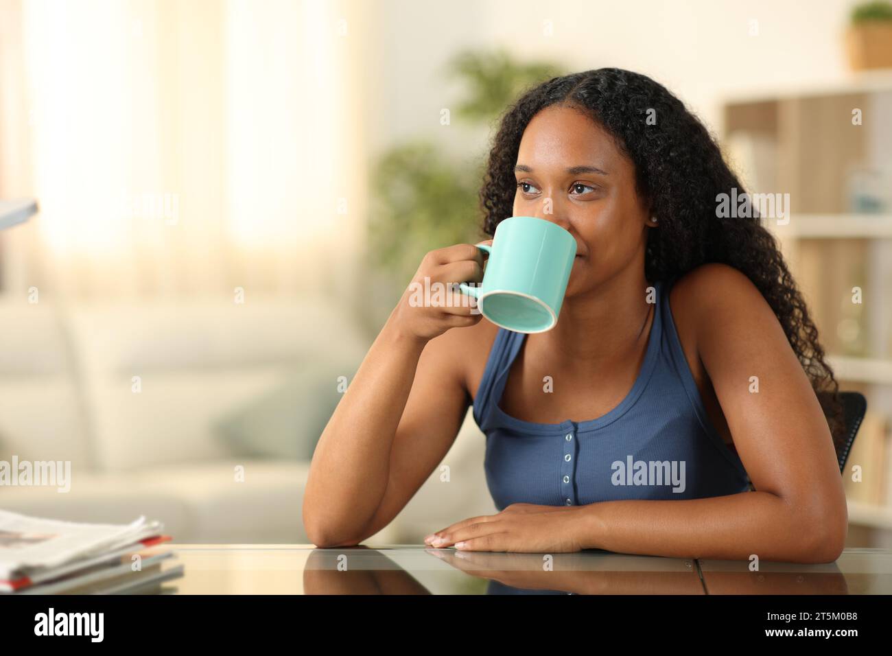 Schwarze Frau trinkt Kaffee zu Hause Stockfoto