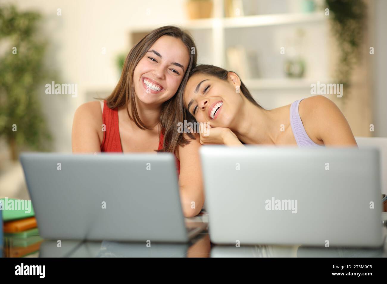 Zwei glückliche Schüler posieren zusammen und schauen zu Hause in die Kamera Stockfoto