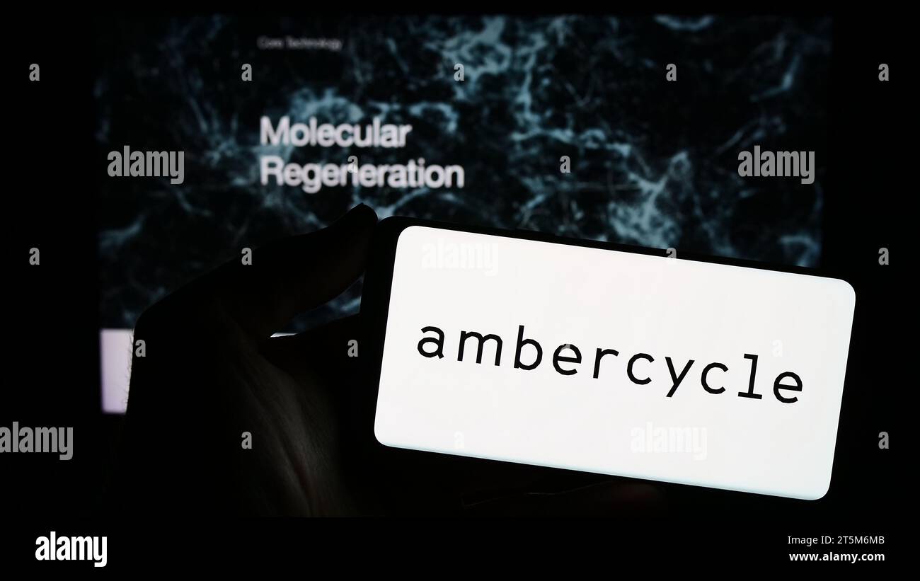 Person mit Smartphone und Logo des US-amerikanischen Materialforschungsunternehmens Ambercycle Inc. Vor der Website. Schwerpunkt auf dem Display des Telefons. Stockfoto