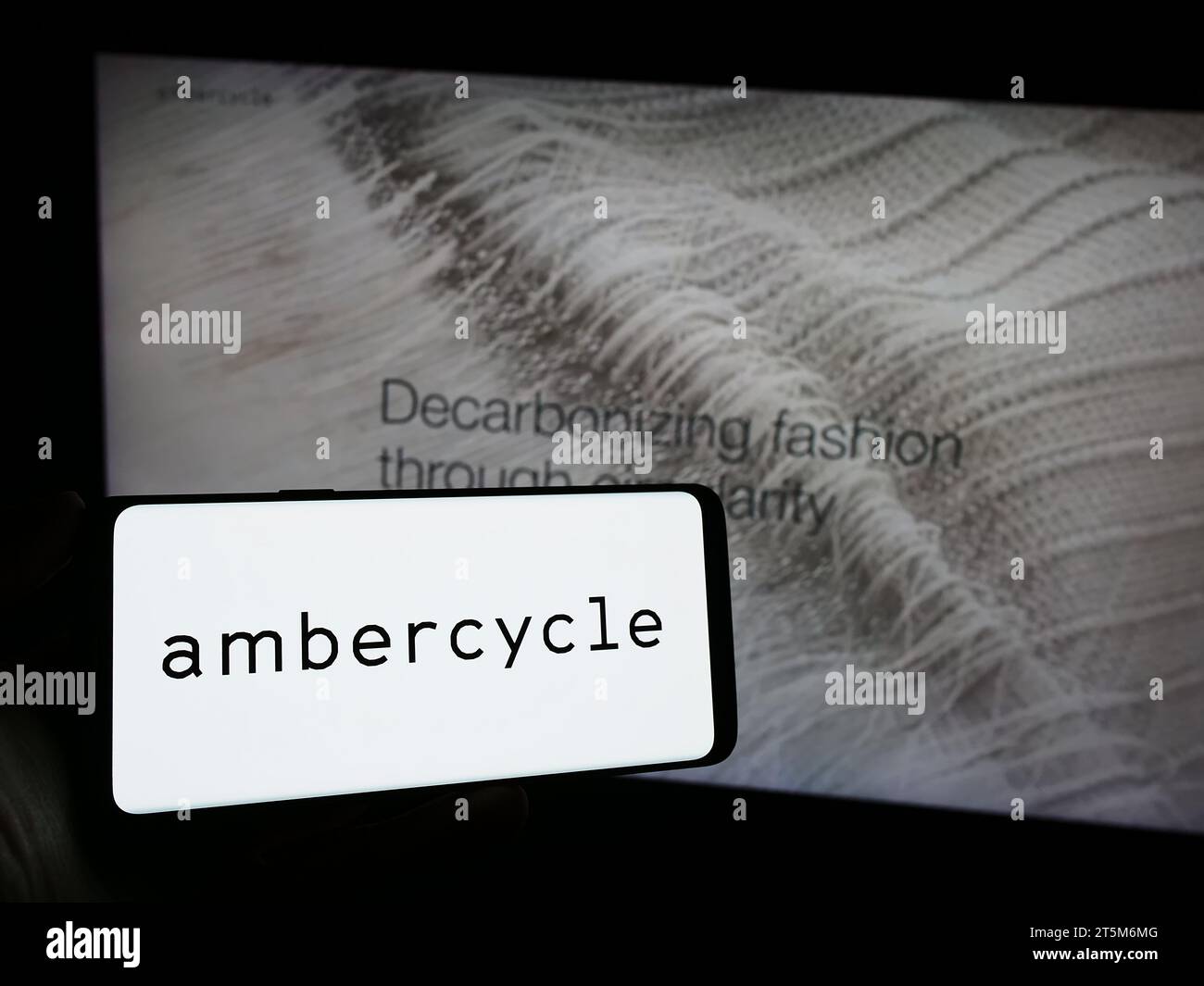 Person, die ein Mobiltelefon mit dem Logo des amerikanischen Materialwissenschaftsunternehmens Ambercycle Inc. Vor der Business-Webseite hält. Schwerpunkt auf dem Display des Telefons. Stockfoto