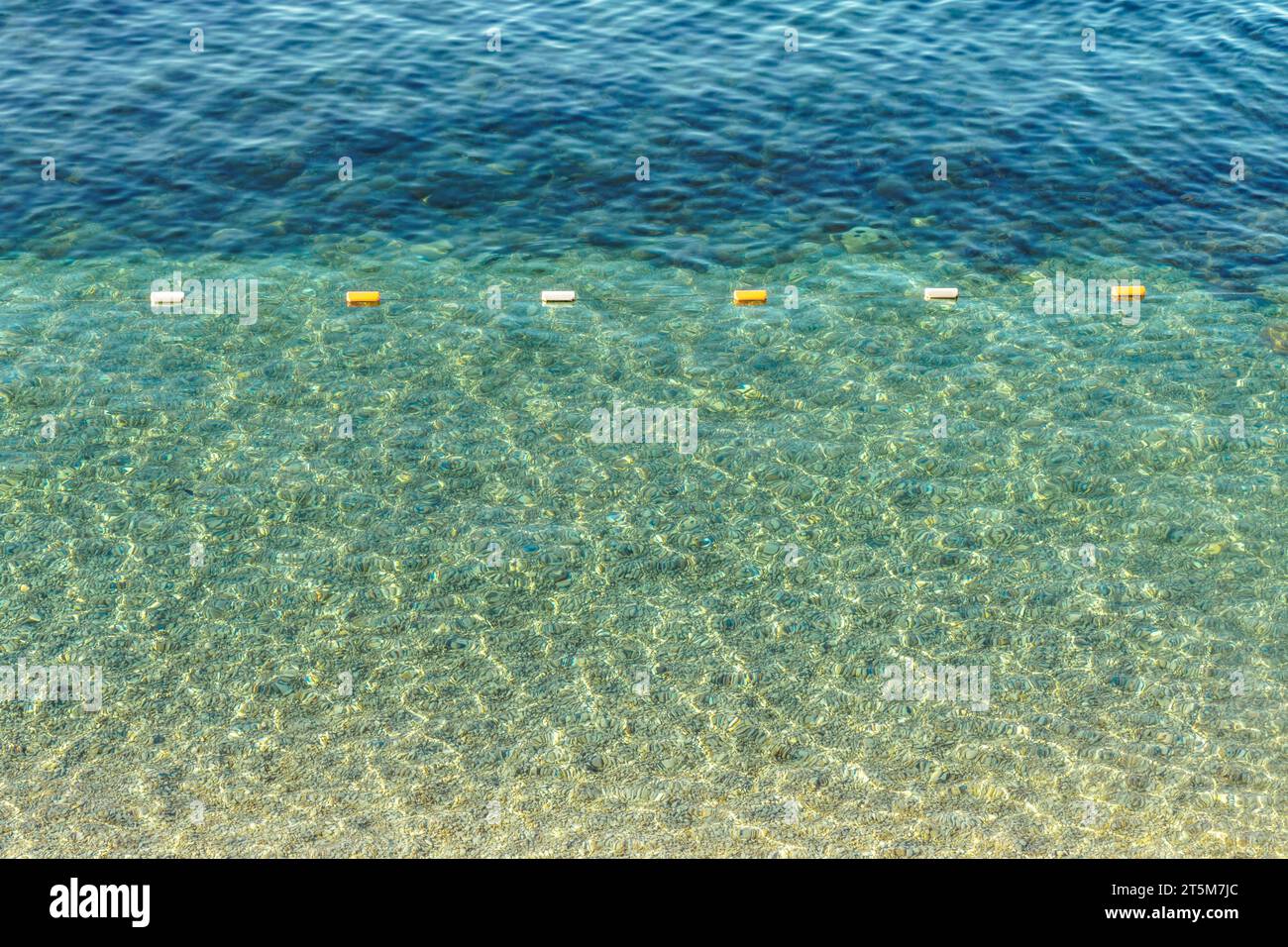Sicherheitsbojen schwebt auf transparenter Wasseroberfläche im Seebad. Markierung für Schwimmer auf klarem Meer an sonnigen Tagen. Ruhige Küstenszene Stockfoto