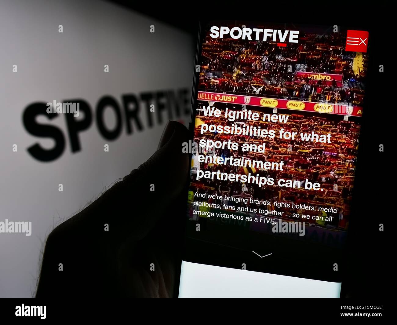 Person, die ein Handy hält, mit der Webseite des internationalen Sportmarketing-Unternehmens Sportfive vor dem Logo. Konzentrieren Sie sich auf die Mitte des Telefondisplays. Stockfoto