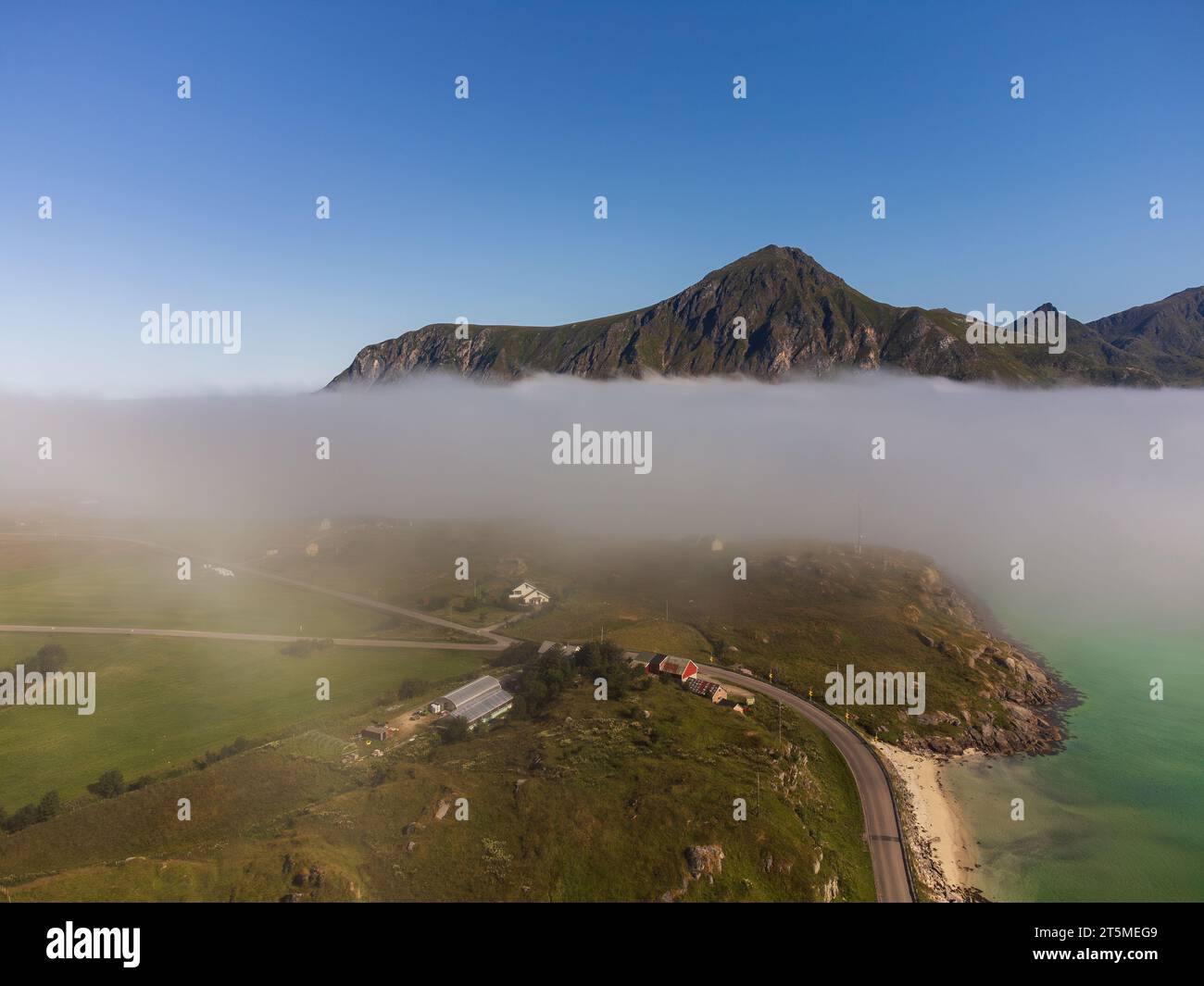 Blick von oben auf eine wunderschöne Landschaft eines Sees in den Bergen Norwegens, mit Nebel, der hereinbricht. E10 Richtung Flakstad. Stockfoto