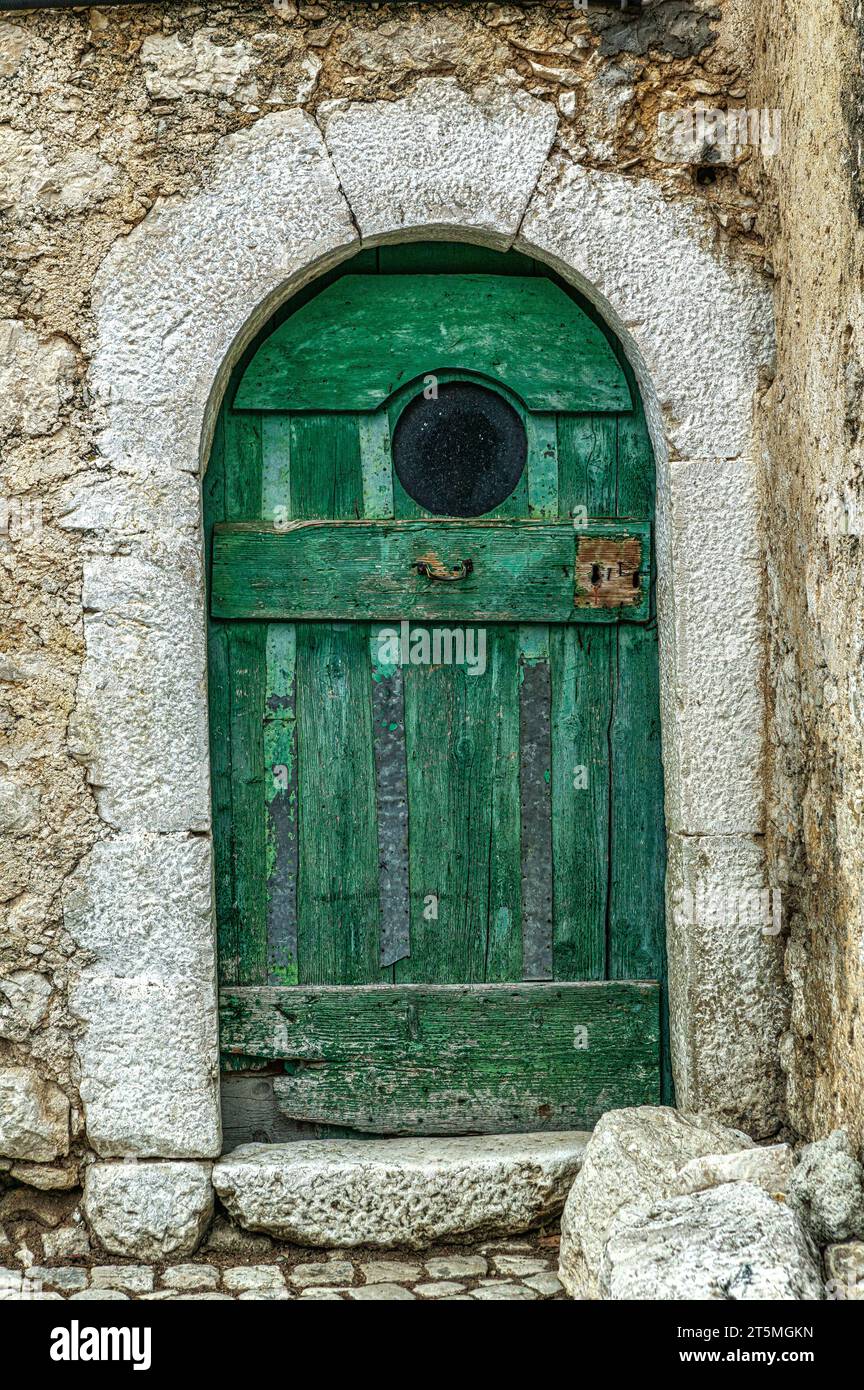 Grüne Tür mit kreisförmigem Bullauge in einem Steinhaus in der kleinen Stadt Civitella Alfedena. Civitella Alfedena, Provinz L'Aquila, Abruzzen, Italien, Stockfoto