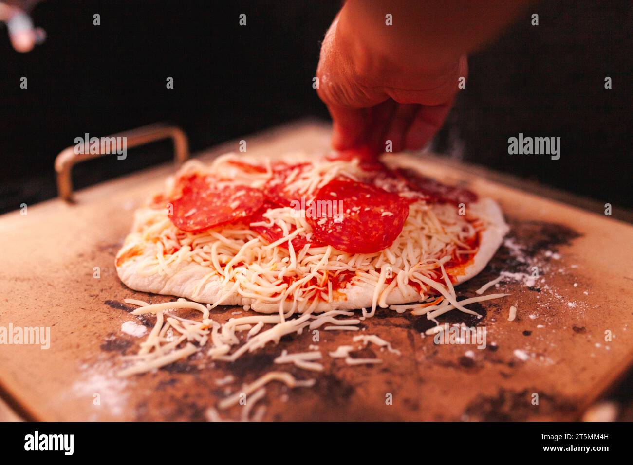 Ein Mann, der seine hausgemachte Peperoni-Pizza fertig macht Stockfoto