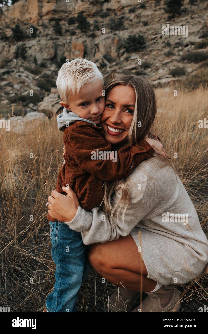 Mutter umarmt den vierjährigen Sohn an einem schönen Herbsttag. Stockfoto