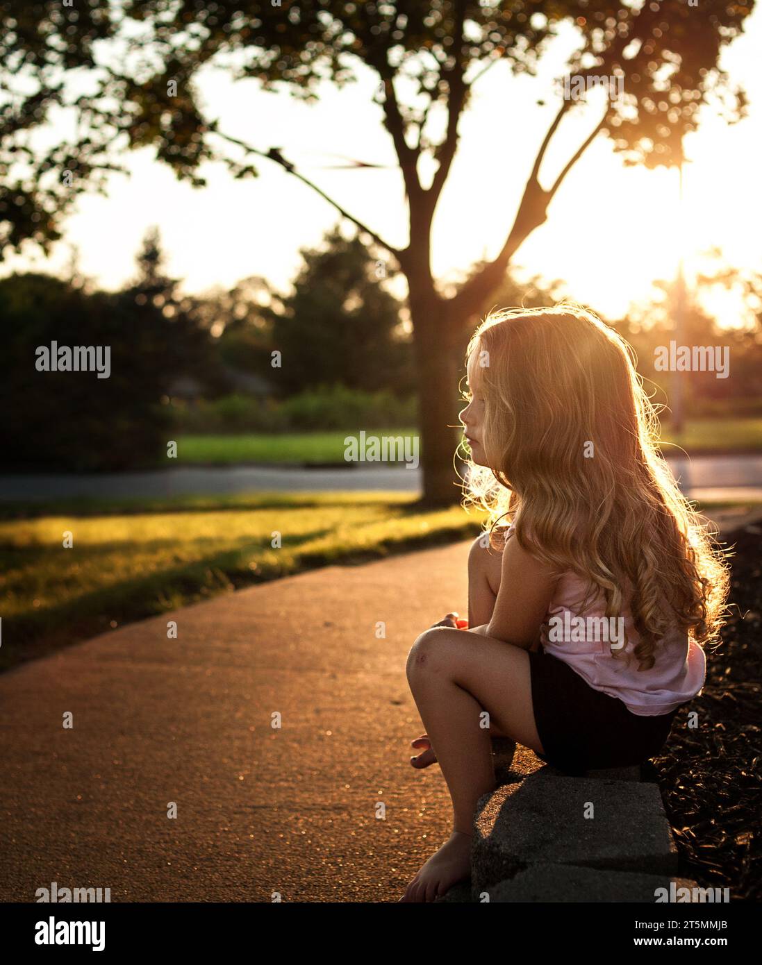 Schönes kleines Mädchen mit langen Locken im Sommer Stockfoto