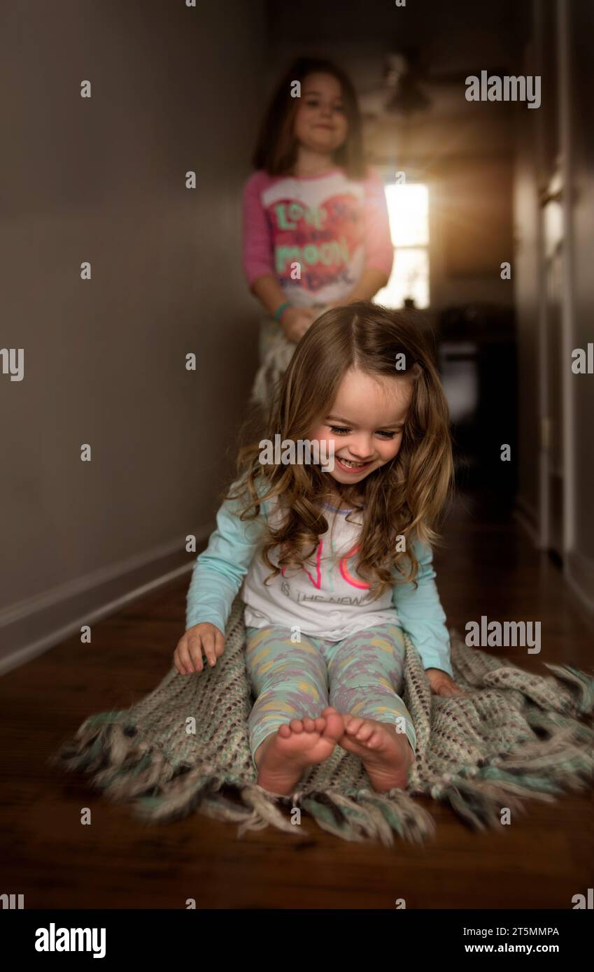 Junge Schwestern spielen und lachen im Flur Stockfoto