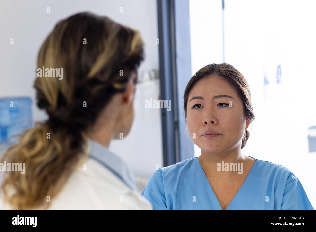 Diverse Ärztinnen sprechen und hören im Krankenhauskorridor Stockfoto